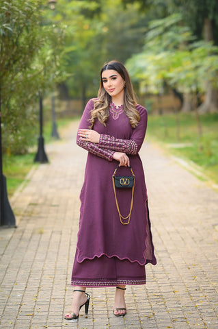 Woman in a purple dress standing on a paved path with greenery in the background